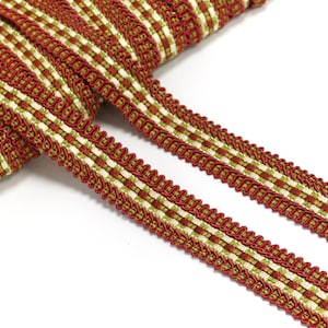 Puede incluir: Borde trenzado rojo y verde con un patrón a cuadros. El borde está tejido con un borde de cordón decorativo.