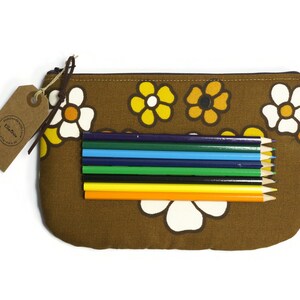 May include: A brown pencil case with a floral pattern featuring white and yellow flowers with orange centers. The case is open and contains a set of colored pencils.
