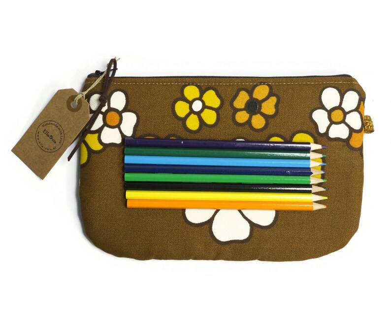 May include: A brown pencil case with a floral pattern featuring white and yellow flowers with orange centers. The case is open and contains a set of colored pencils.
