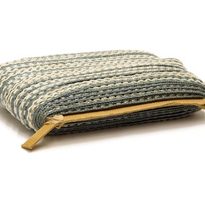 May include: A roll of blue and white striped trim with a brown leather edge. The trim is folded in half and the leather edge is visible.