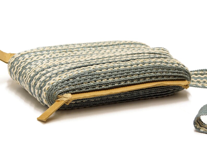 May include: A roll of blue and white striped trim with a brown leather edge. The trim is folded in half and the leather edge is visible.