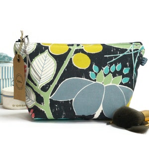 Könnte beinhalten: Eine schwarze Kosmetiktasche mit floralem Druck, Reißverschluss und Kordelzug. Die Tasche hat ein blaues, grünes, gelbes und weißes Blumenmuster auf schwarzem Hintergrund.