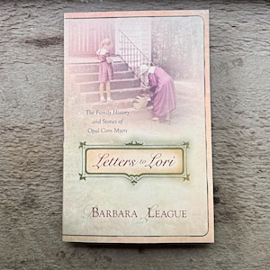 May include: A book titled "Letters to Lori" by Barbara League. The cover features a sepia-toned illustration of two women on a porch. The book's subtitle reads "The Family History and Stories of Opal Corn Myers."