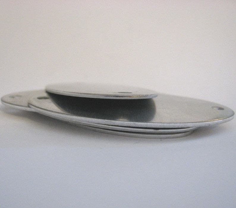 May include: Three silver oval-shaped metal discs stacked on top of each other.