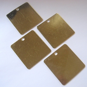 May include: Four square brass tags with a hole in the top corner. The tags are blank and have a brushed finish.