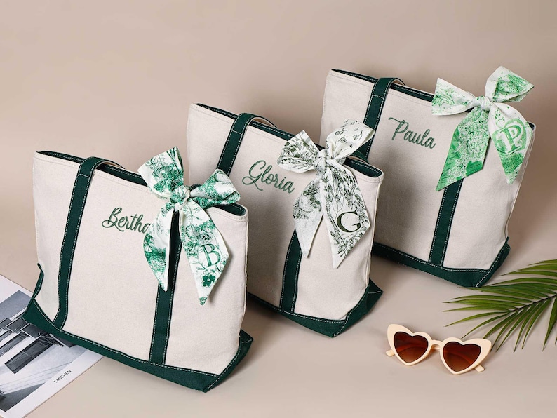 Peut inclure: Trois sacs cabas en toile blanche avec des bordures vertes et des noms personnalis&eacute;s&nbsp;: Bertha, Gloria et Paula. Chaque sac est orn&eacute; d&rsquo;un ruban &agrave; motif vert et blanc nou&eacute; en un n&oelig;ud.