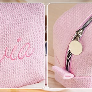 May include: A light pink waffle-textured cosmetic bag featuring the embroidered name Olivia in a matching pink script font. The bag includes a silver-toned metal zip closure with a round, smooth, blank metal pull tab attached to the slider.