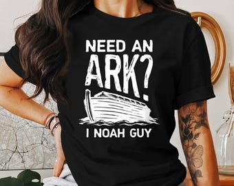 May include: Black t-shirt featuring the text "NEED AN ARK?" above a white illustration of Noah's Ark, with the text "I NOAH GUY" below. A casual wear item with a humorous religious theme.