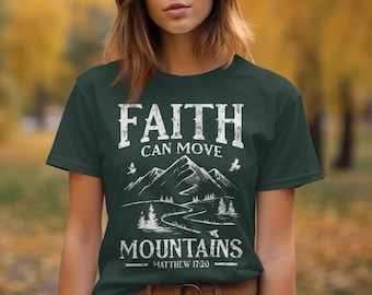 Può includere: T-shirt verde scuro con la scritta bianca "FAITH CAN MOVE MOUNTAINS" e un disegno di montagna e paesaggio. La maglietta include anche il versetto biblico Matteo 17:20.