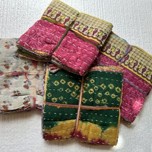 May include: A set of four kantha quilts in various colours and patterns, including floral, paisley, and geometric designs. The quilts are made from recycled saris and are hand-stitched.