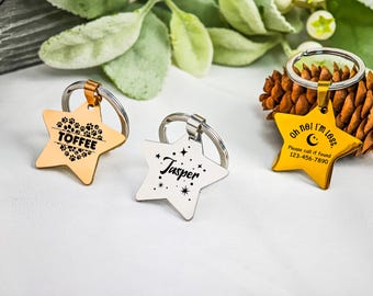 Puede incluir: Tres etiquetas de identificación para mascotas en forma de estrella con llaveros. Una es dorada con huellas de patas y el nombre "Toffee". Otra es plateada con el nombre "Jasper". La tercera es amarilla con el texto "Oh no! I'm lost" y un número de teléfono.