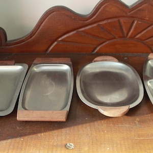May include: Four silver serving trays with wooden handles. The trays are arranged on a wooden surface.