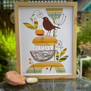 May include: A framed print of a stylized bird perched on a nest with abstract foliage and geometric shapes in shades of brown, yellow, green, and blue. The print is titled "Songbird" and signed by the artist.