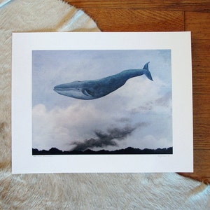 May include: A watercolor painting of a blue whale flying through a cloudy sky. The whale is facing left and has a dark blue body with a lighter blue underside. The sky is a light blue with white clouds and a dark gray cloud in the distance.