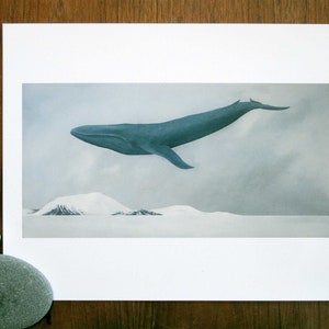 May include: A blue whale flies over a snowy landscape. The whale is in mid-air, with its body angled slightly upwards. The background is a light blue sky with white clouds.
