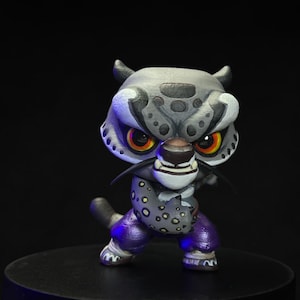 Può includere: Una piccola statuetta di leopardo delle nevi grigia e bianca con accenti viola e gialli. La statuetta è in posa da combattimento con la bocca aperta e gli occhi spalancati.