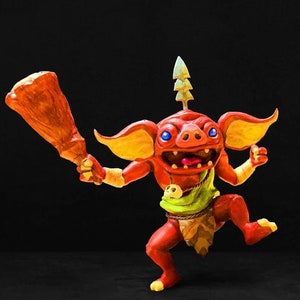 May include: A red and orange goblin figurine with a pointed hat and a club. The goblin is wearing a green loincloth and has a toothy grin.