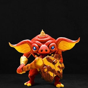 May include: A red and yellow fantasy creature with a pointed head and large ears holds a wooden club and a shield. The creature has a fierce expression and appears to be ready for battle.