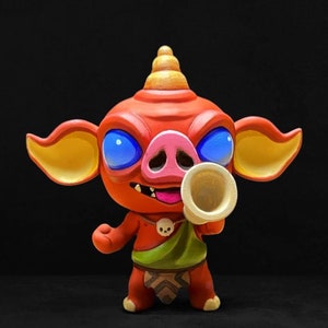May include: A red and yellow cartoon figurine of a pig-like creature with a horn, holding a white horn. The creature has blue eyes and a pink snout.