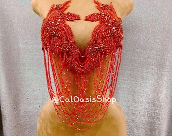 May include: A red beaded top with intricate floral-like designs and cascading beaded strands. The top is displayed on a mannequin. The text "@CalOasisShop" is visible on the garment.