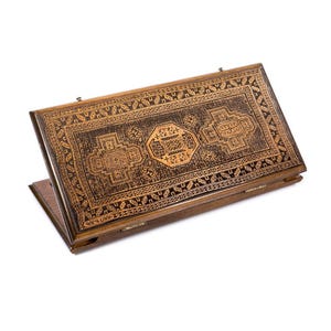May include: Wooden backgammon board with intricate, geometric carvings in shades of brown and gold. The board is open, revealing the playing surface with detailed patterns. The design includes Armenian text.