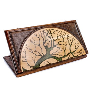May include: A wooden game box with a brown leather-like exterior and a decorative tree of life design on the lid. The tree is intricately carved and painted in shades of green and brown.