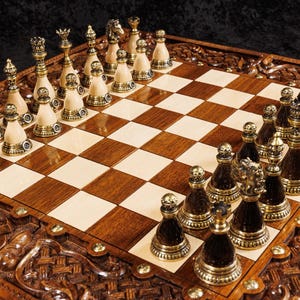 May include: A detailed wooden chess set with intricately carved borders. The chess pieces are gold and ivory-colored, arranged on a brown and cream checkered board. The set is designed for strategic board games.