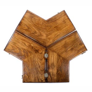 Puede incluir: Una caja de madera en forma de estrella con un acabado marrón oscuro. La caja está dividida en secciones, con bisagras y un asa central. La veta de la madera es visible y la caja parece estar hecha a mano.