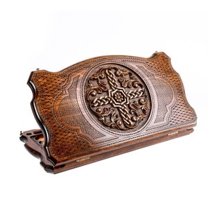 May include: A wooden game board with intricate carvings. The board is closed and has a Celtic knot design in the center. The board is made of dark wood and has a polished finish.