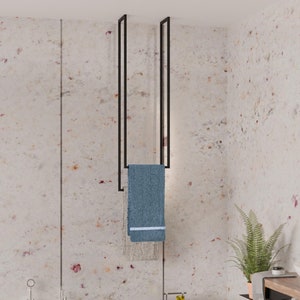 May include: A black metal towel rack with two bars hanging from the ceiling. A blue towel is hanging on the rack. A white bathtub is in the foreground.
