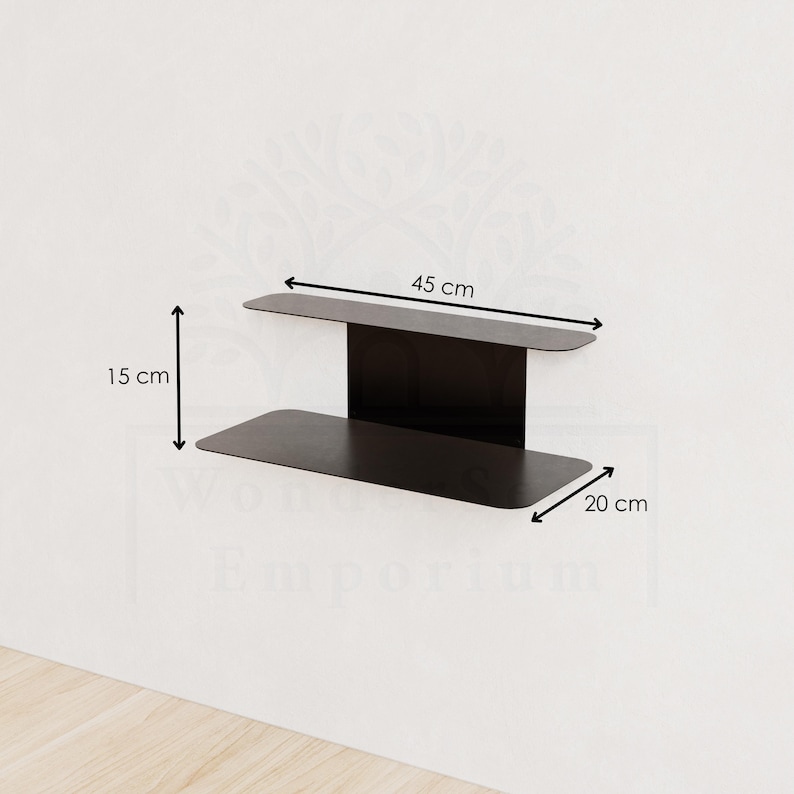 May include: A black metal wall shelf. The shelf is 45 cm wide, 15 cm high, and 20 cm deep. The shelf has a modern design and is mounted on a white wall. The shelf is empty.