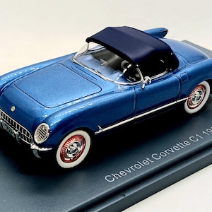 Peut inclure: Une miniature de Chevrolet Corvette C1 de 1953 de couleur bleue avec un toit convertible noir. La voiture est exposée sur une base grise avec le texte "Chevrolet Corvette C1 1953".