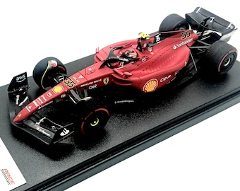 May include: A red and black 1:18 scale model of a Formula 1 race car with the number 55 on the side. The car has the words "Richard Mille" and "Santander" on the side. The car is on a black display base.