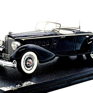 Op de afbeelding: Een donkerblauw schaalmodel van een cabriolet met chromen bumpers, een verticale grille, ronde koplampen en whitewall-banden. De voorste nummerplaat toont de tekst 2E 73 02 en een metalen plaatje op de voet vermeldt 55 of 288.