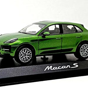 以下が含まれることがあります： ポルシェマカンSの緑色のダイキャストモデルカー。ミニチュアカーは詳細なホイール、黒いインテリアを備え、黒いディスプレイスタンドに置かれています。「Macan S」の文字がスタンドに表示されています。