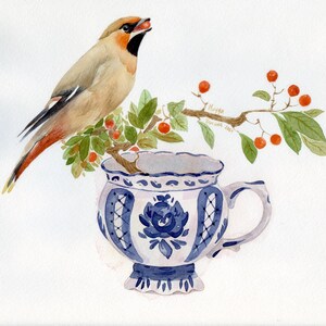 L'uccello Waxwing Boho seduto su un ramo con bacche rosse floreali in una tazza da tè in porcellana e con in mano una bacca rossa nel becco
