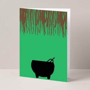 May include: Greeting card with a green background and a black cauldron illustration. The top of the card features a brown, textured design. The cauldron has a handle and is set against a green backdrop.