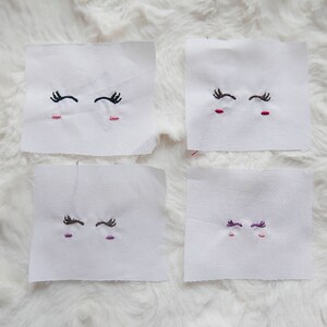 May include: Four white fabric squares with embroidered eyes. The eyes are black, brown, purple, and brown. The fabric squares are labelled with embroidery file formats: PES, DST, EXP, HUS, JEF, PCS, PEC, UP3, XXX.