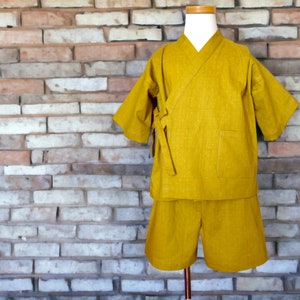 May include: A yellow short-sleeved top and matching shorts set. The top has a traditional Japanese style with a wide collar and a sash tie. The fabric has a subtle texture.