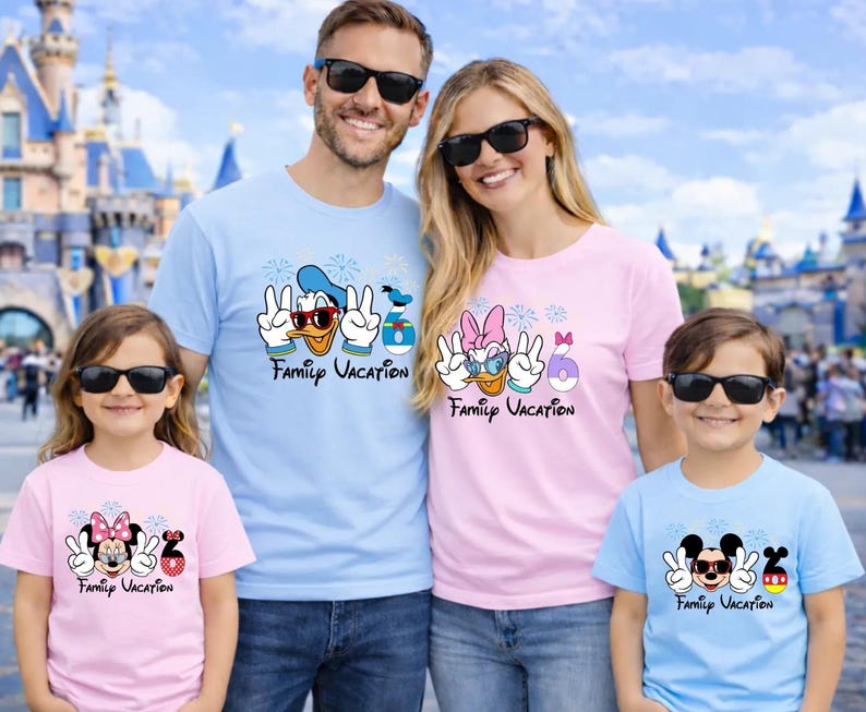 A family of four, consisting of a man, a woman, and two children, posing together in front of a Disney castle. They are all wearing matching t-shirts with Disney characters and the text "Family Vacation".