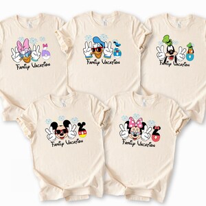 five beige t-shirts with various Disney character designs and the text "Family Vacation" printed on them.