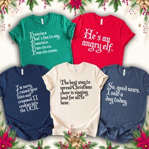 Peut inclure: Cinq t-shirts &agrave; manches courtes de couleurs vari&eacute;es, chacun avec un motif de texte blanc unique. Les chemises sont vertes, rouges, bleu marine, cr&egrave;me et bleu fonc&eacute;. Le texte sur les chemises comprend des phrases humoristiques et de No&euml;l.