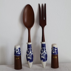Può includere: Un set di cucchiaio e forchetta in legno con manici in porcellana blu e bianca, insieme a due saliere e pepiere abbinate. I manici presentano un motivo floreale blu. Il sale ha la lettera "P".