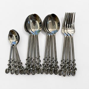 May include: A set of stainless steel flatware featuring a polished silver finish. The collection includes small spoons, large spoons, and forks, all characterized by a distinctive twisted metal handle design that spirals toward the base.