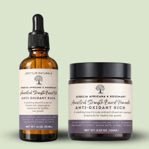 Op de afbeelding: Twee bruine glazen flessen met baardverzorgingsproducten. Eén is een druppelflesje met baardolie, de andere is een potje met baardpommade. Beide hebben labels met de tekst "Ancestral Strength" en "Anti-Oxidant Rich". De olie is 50 ml, en de pommade is 120 ml.