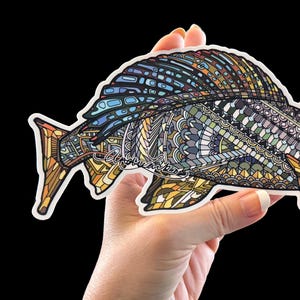 Può includere: Un adesivo colorato e dettagliato di un pesce con motivi intricati in tonalità di blu, verde, giallo e arancione. Il pesce ha un design stilizzato con una grande pinna arrotondata e una piccola coda appuntita.