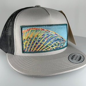 Puede incluir: Una gorra de camionero gris y negra con un pez colorido bordado en la parte delantera. La gorra tiene una parte trasera de malla negra y un panel frontal gris. El pez es de un azul, verde, amarillo y naranja vibrantes.