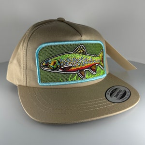 May include: A tan,  snapback baseball cap with a green, blue, and orange embroidered trout patch. The patch has the text "Brook Trout" on it.