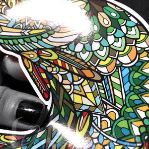 May include: A colorful sticker of a fish with a detailed, intricate design. The fish is green, blue, yellow, red, and white.