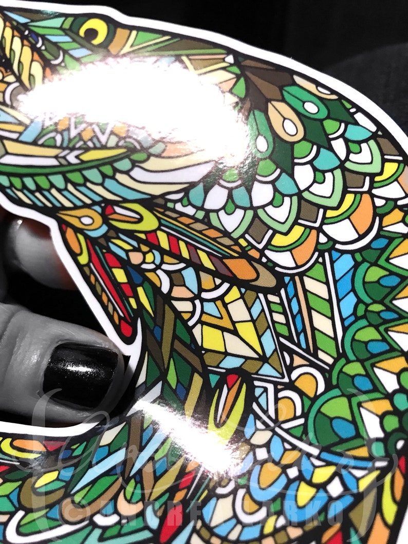 May include: A colorful sticker of a fish with a detailed, intricate design. The fish is green, blue, yellow, red, and white.